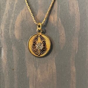 Vintage pendant in gold tone filigree and a single rhinestone. Measures 1/2 inch